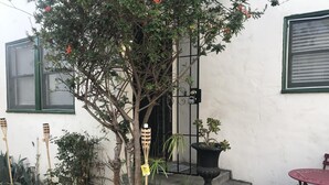 A small outdoor area with a potted plant, a welcome sign, and a table with chairs. - LARGE STUDIO, IN GREAT NEIGHBORHOOD,PET FRIENDLY, PLENTY OF PARKING (Long Beach)
