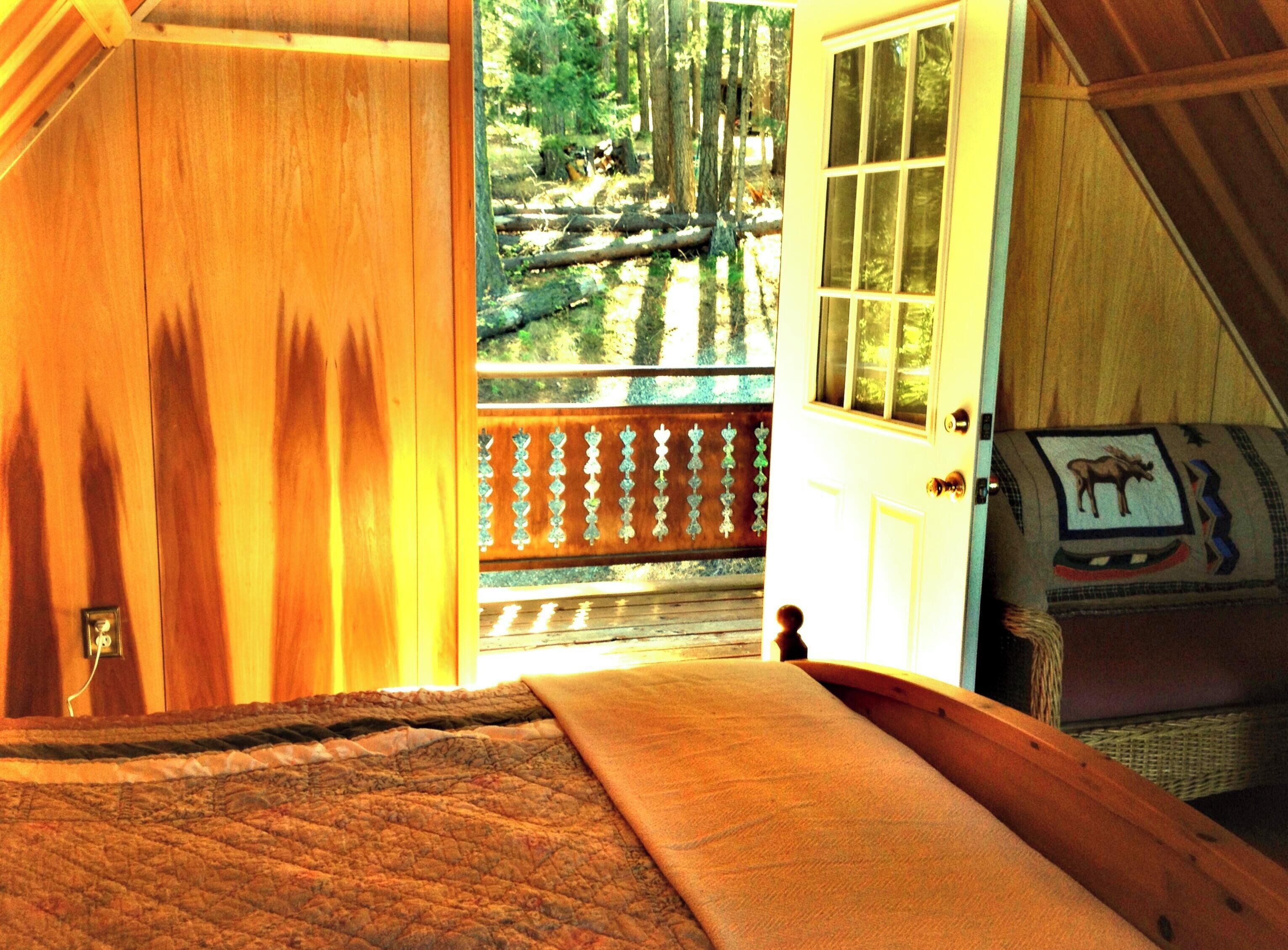 A wooden door leading to a balcony with a view of a forested area.