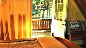 A wooden door leading to a balcony with a view of a forested area.