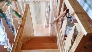 A narrow wooden staircase with a handrail, leading to a room with a wooden floor and a curtain.