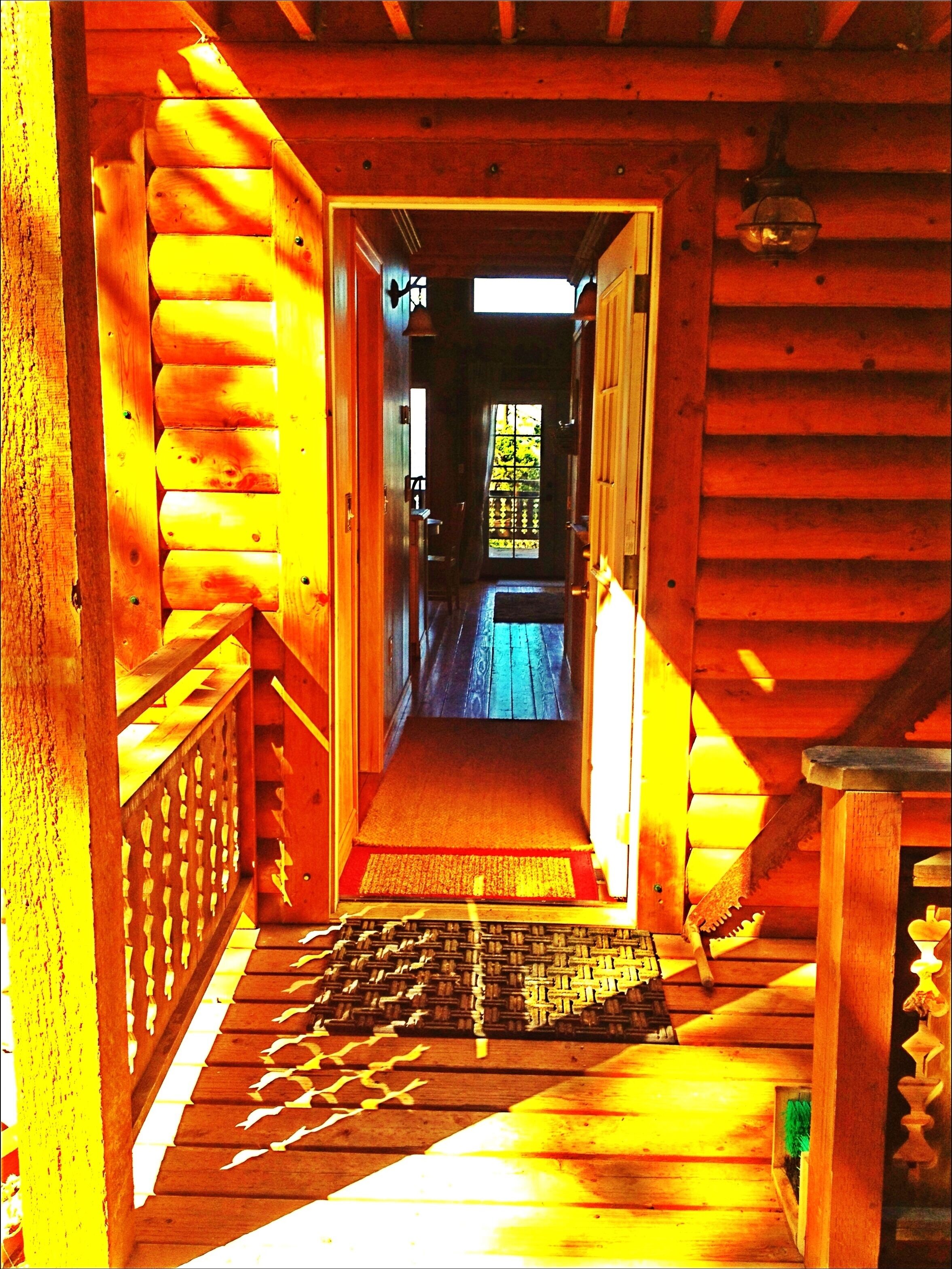 A wooden hallway with a view to a room with a window.