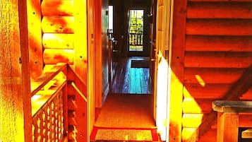 A wooden hallway with a view to a room with a window.