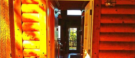A wooden hallway with a view to a room with a window.