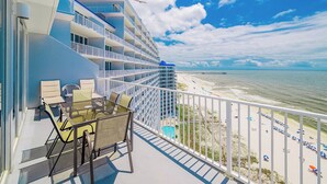 A balcony with outdoor seating, a view of the beach, and a pier in the distance. - LIGHTHOUSE! Popular Property! ~ 1 BR Beach Front! XTRA BATH! (Gulf Shores)