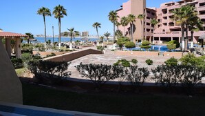 A resort with a pool, palm trees, and a view of the beach.