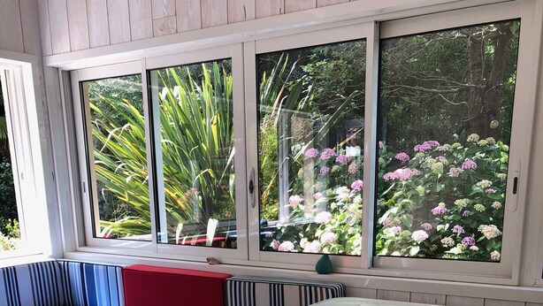 Ein Whirlpool mit Blick auf einen Garten durch große Fenster.
