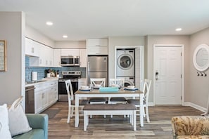 A compact kitchen with modern appliances, a dining area with a table and chairs, and a laundry room with a washing machine.
