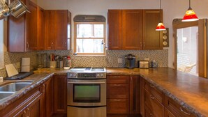 A kitchen with wooden cabinets, a stainless steel oven, and a window providing natural light. - Ski in Ski Out From 10,000' Where Living in the Mountains is all it Should be (Angel Fire)