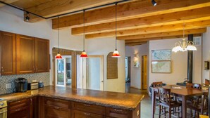 A kitchen with wooden cabinets, a granite countertop, pendant lights, and a dining area with wooden chairs and a table. - Ski in Ski Out From 10,000' Where Living in the Mountains is all it Should be (Angel Fire)