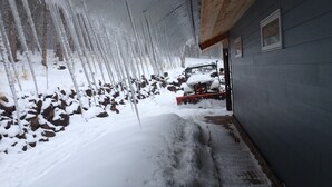 A snow-covered outdoor area with a vehicle and a building. - Ski in Ski Out From 10,000' Where Living in the Mountains is all it Should be (Angel Fire)