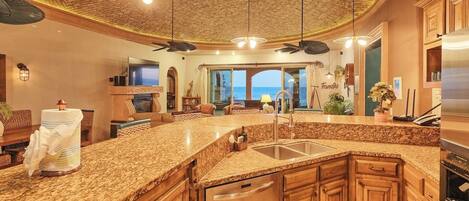 A spacious kitchen with granite countertops, wooden cabinets, and a large island with a sink.