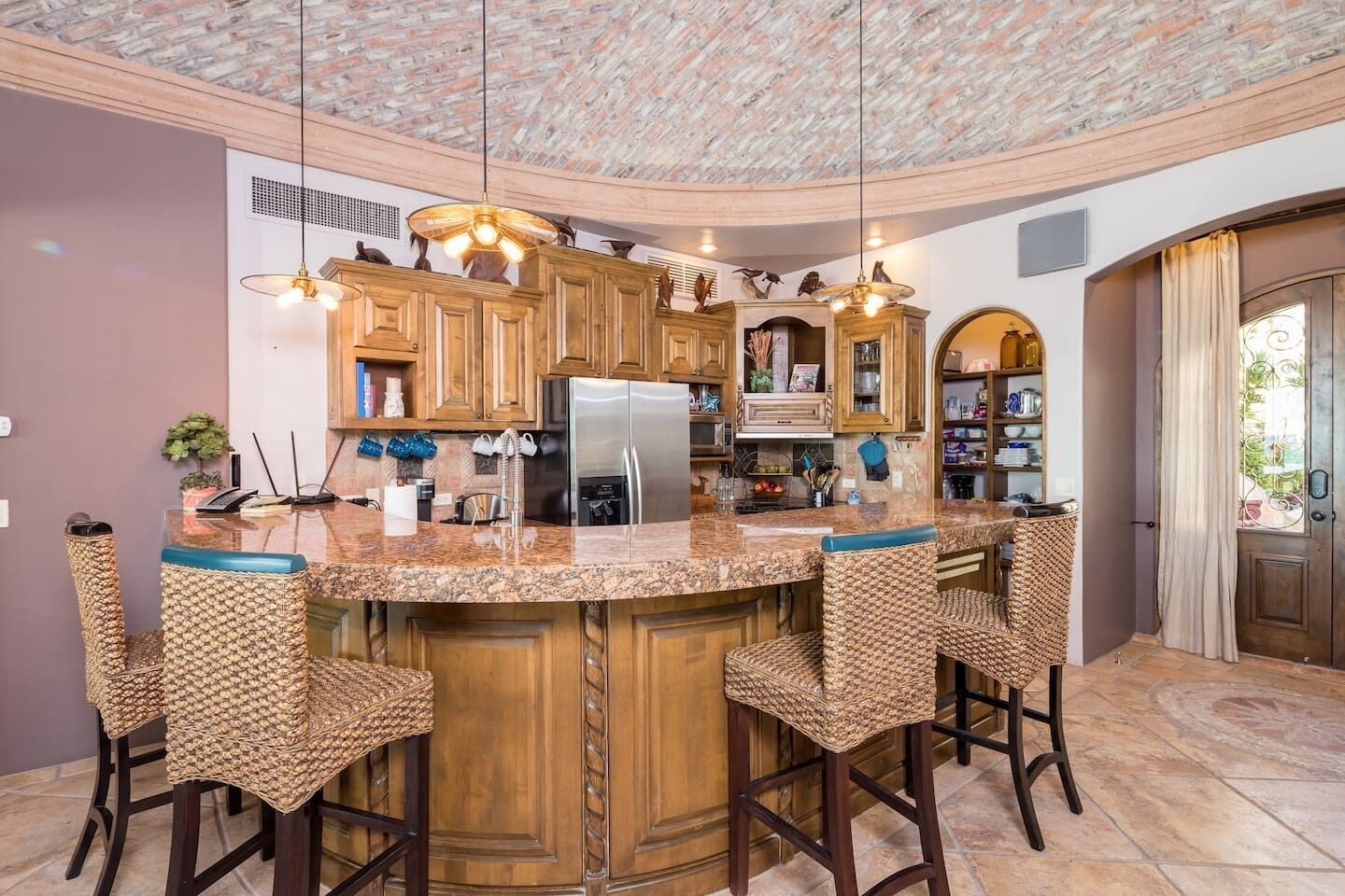 A kitchen with a central island, wooden cabinets, and bar stools.