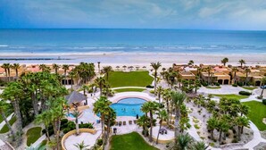 A resort with a swimming pool, palm trees, and a beach view.