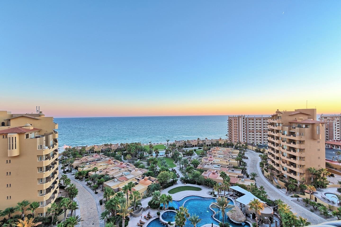 A resort with multiple buildings, a central pool area, and a view of the sea.