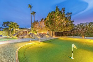 A golf course with a putting green, a flag, and a stone wall. - Experience luxury in Scottsdale with heated pool, hot tub, pickleball, & slide! (Scottsdale)
