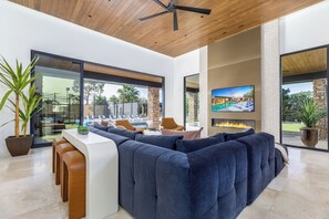 A modern living area with a large sectional sofa, a bar area, and a television screen. - Experience luxury in Scottsdale with heated pool, hot tub, pickleball, & slide! (Scottsdale)