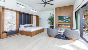 A modern bedroom with a large bed, a ceiling fan, a fireplace, and a view of the outdoors. - Experience luxury in Central Scottsdale with heated pool, pickleball, & slide! (Scottsdale)