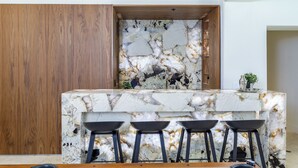A kitchen with a marble countertop and three black bar stools. - Experience luxury in Central Scottsdale with heated pool, pickleball, & slide! (Scottsdale)