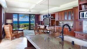 Una cocina con una isla grande, armarios de madera y vista al océano.