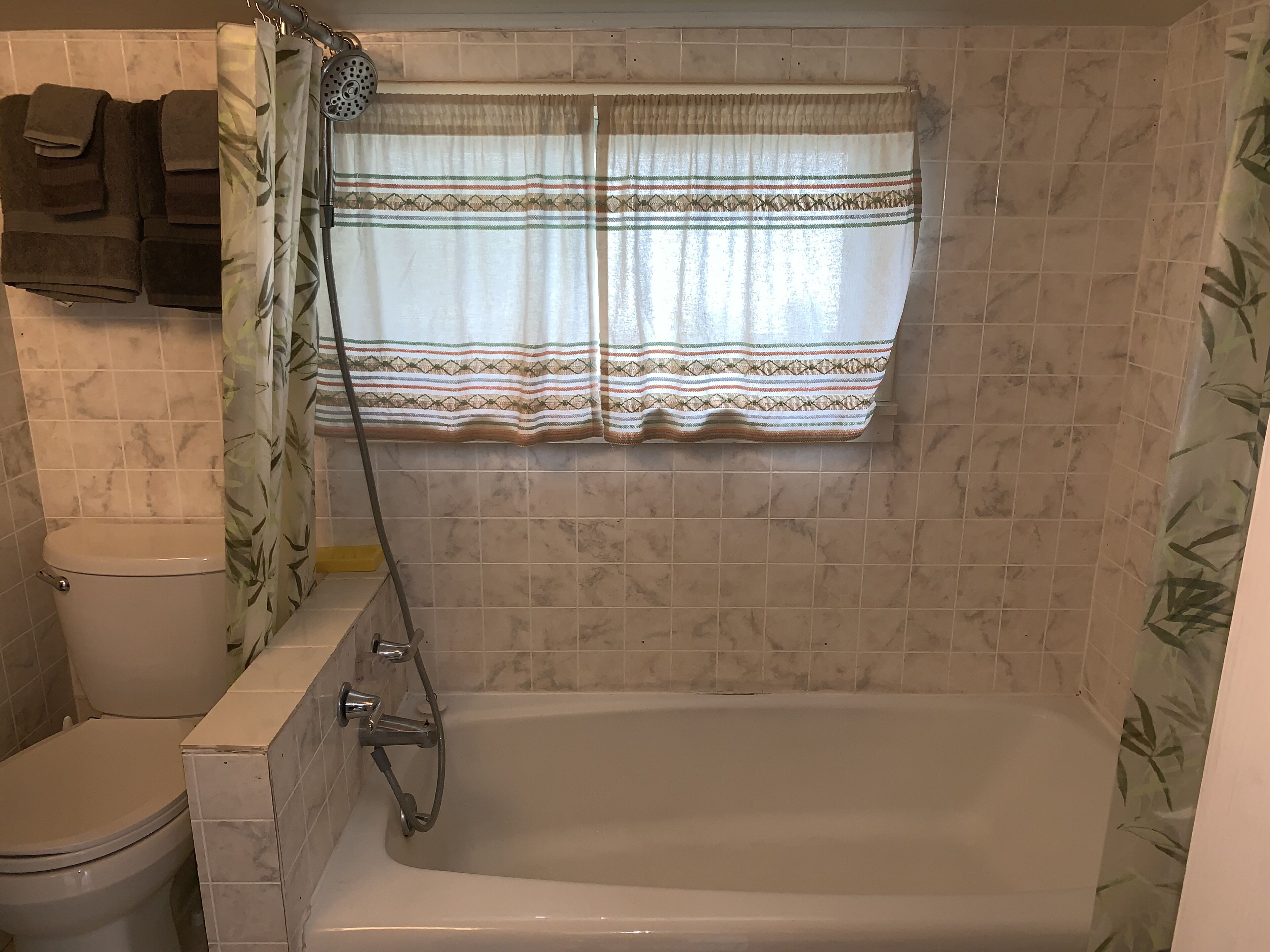 Un baño con bañera, inodoro y cortina de ducha.