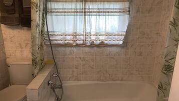 Un baño con bañera, inodoro y cortina de ducha.
