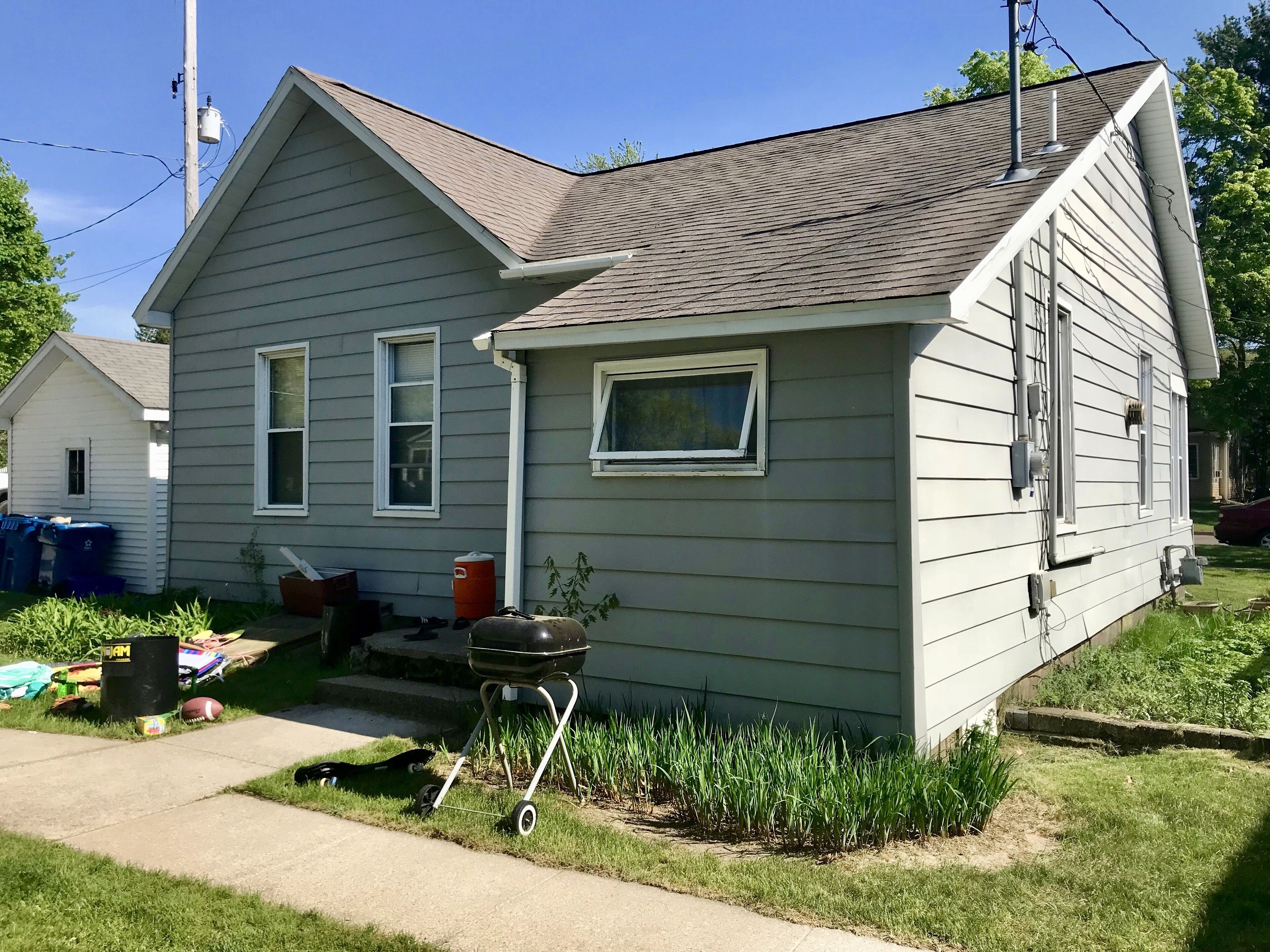Une maison de plain-pied avec un toit en pente, un porche à l’avant et un petit jardin devant.