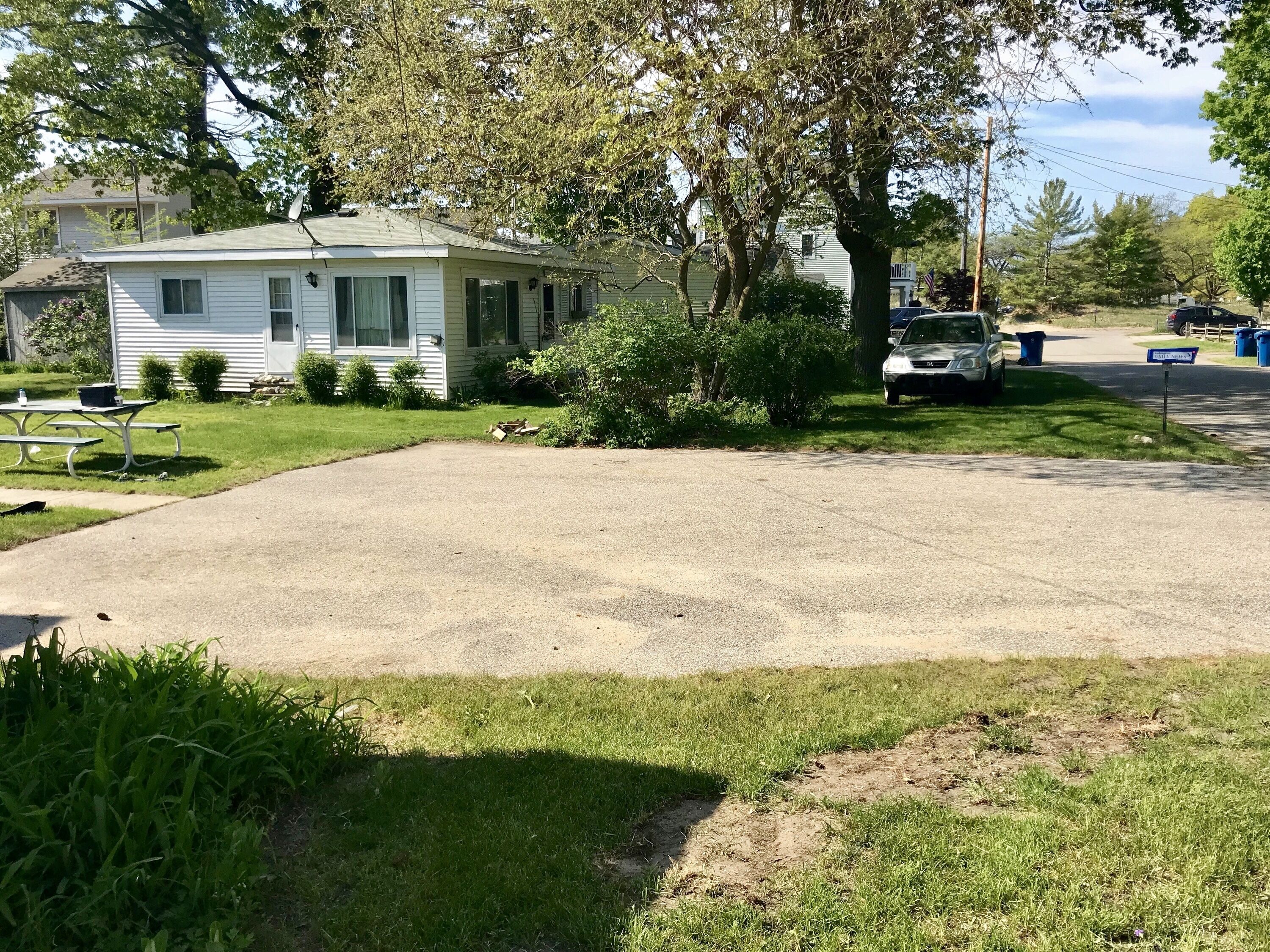 Una casa móvil de un piso con jardín delantero, una mesa de picnic y un coche aparcado.