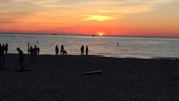 A beach at sunset with people walking and playing.