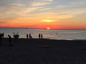 Una playa al atardecer con gente caminando y jugando.