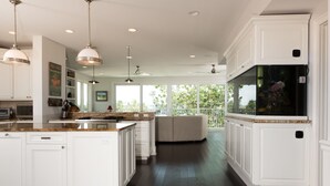 A spacious kitchen with white cabinetry, granite countertops, and pendant lighting.