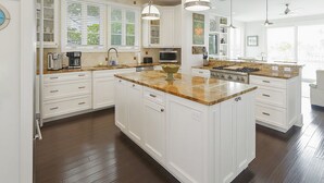 A spacious kitchen with white cabinetry, granite countertops, and pendant lighting.