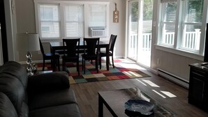 A living room with a black leather couch, a coffee table, and a dining area with a table and chairs.