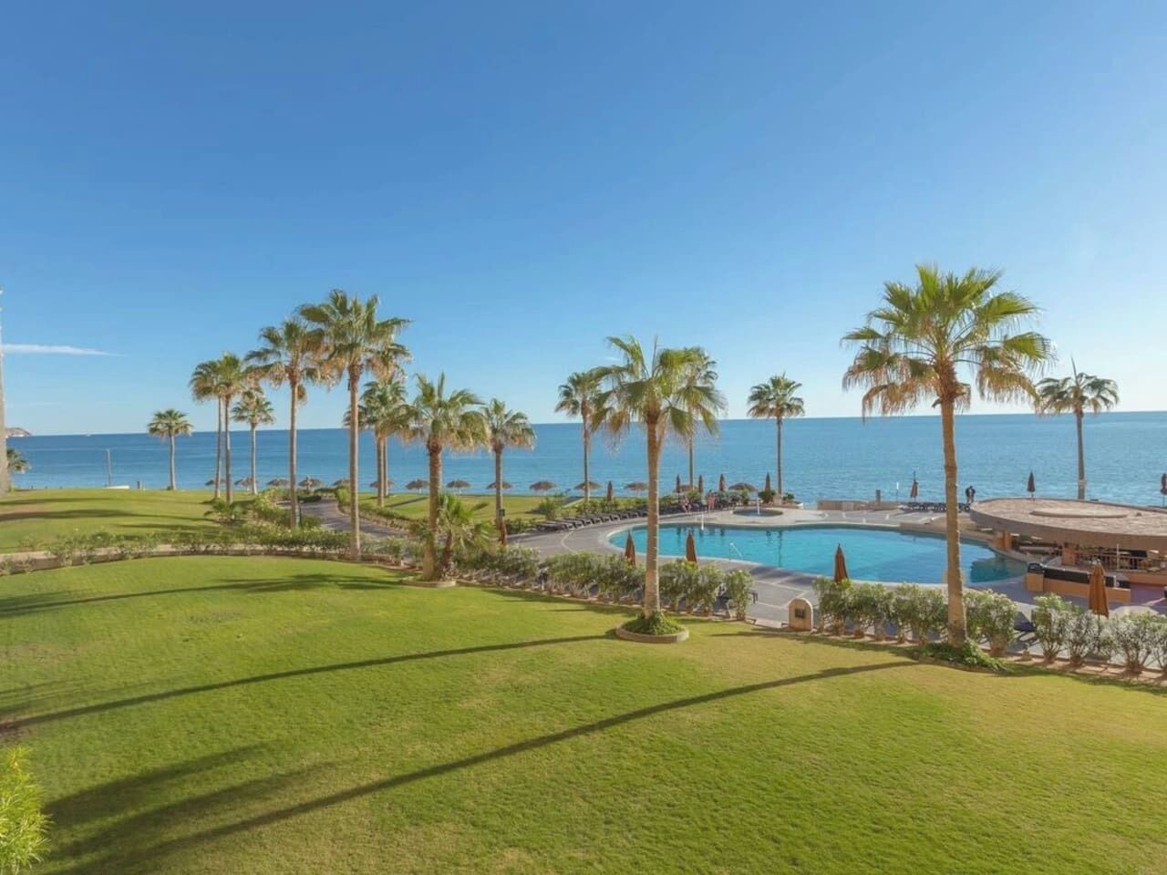 Ett semesterparadis med pool, palmer och utsikt över havet.