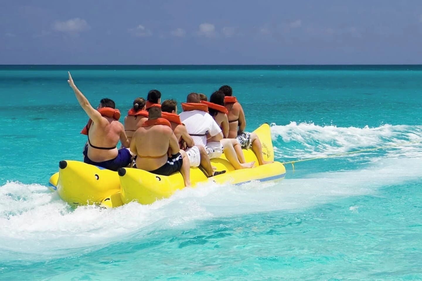 Eine Gruppe von Menschen auf einer gelben Flößchen in klarem türkisblauem Wasser.