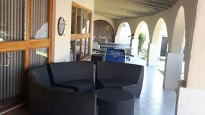 Un espace extérieur aménagé en terrasse, avec des meubles en osier, une table de ping-pong et un jeu de fléchettes.