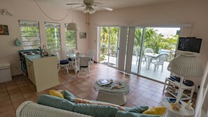 Un vaste espace de vie comprenant un canapé, une table à manger et des chaises, un coin cuisine et un balcon offrant une vue sur l’extérieur.