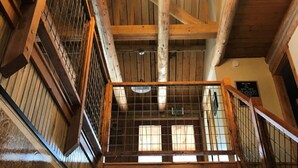 Un interior de madera con techo alto, una araña y una escalera con barandilla.