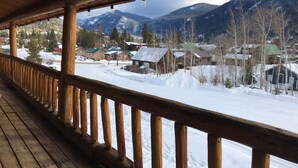 Eine hölzerne Veranda mit Blick auf ein verschneites Dorf und Berge.