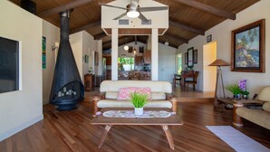 A spacious living room with a high ceiling, a fireplace, a sofa, and a dining area in the background. - Breath taking ocean and volcano views! Pool,Close to beaches and everything else (Kihei)
