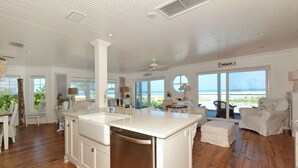 A spacious kitchen with a large island, white cabinetry, and a view of the beach. -  Beautiful, Gulf-Front Home on Bean Point--Halcyon House (Anna Maria)