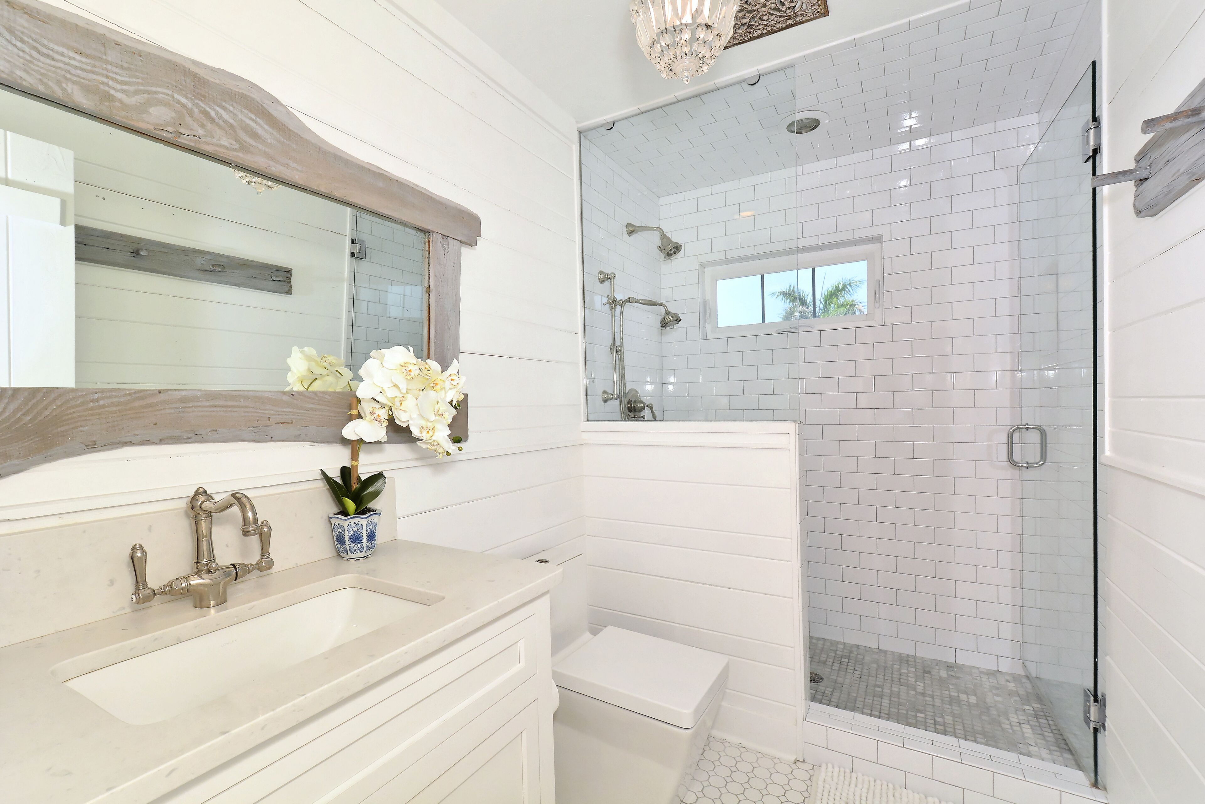 A modern bathroom with a large mirror, a sink, a toilet, and a glass-enclosed shower area.