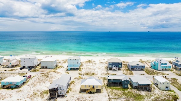 A beachfront property with multiple buildings, some with elevated structures, and a clear view of the ocean.