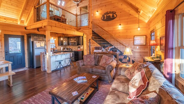 A spacious wooden cabin interior with a living room, kitchen, and a balcony. - Family-Friendly Log Cabin with Hot Tub, Fire Pit & Game Room – Pet Welcome! (Hendersonville)