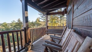 A wooden deck with benches, a railing, and a view of trees. - Family-Friendly Log Cabin with Hot Tub, Fire Pit & Game Room – Pet Welcome! (Hendersonville)