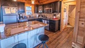 A modern kitchen with granite countertops, stainless steel appliances, and wooden cabinetry. - Family-Friendly Log Cabin with Hot Tub, Fire Pit & Game Room – Pet Welcome! (Hendersonville)