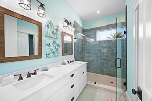 Une salle de bain avec un meuble-lavabo blanc, une cabine de douche en verre et un grand miroir.