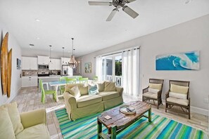 Un salon moderne comprenant un canapé, des fauteuils, une table basse et un coin repas avec une table et des chaises.