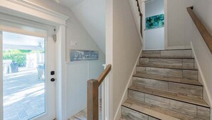 Eine Treppe mit Holzbalken und einer Handläufe, eine Tür mit einer Glasscheibe sowie ein an der Wand befestigtes Schild mit der Aufschrift 'Florida'.