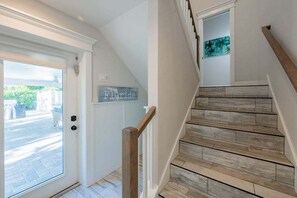 Un escalier avec des marches en bois et une rampe, une porte avec un panneau de verre et une enseigne fixée au mur sur laquelle on peut lire « Floride ».