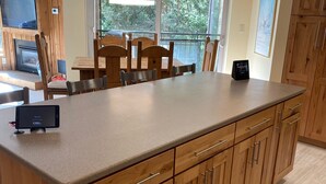 A modern kitchen with wooden cabinets, a large island, and a dining area with wooden chairs. - short walk to Quicksilver lift, bars & restaurants. (Breckenridge)